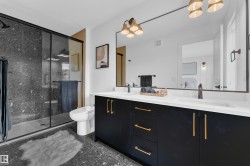 Modern bathroom featuring a spacious glass-enclosed shower with dark tile surround - 