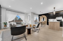 Open-concept living space featuring light wood-finish flooring, recessed lighting, and a large window with sheer white drapery - 
