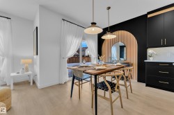 Dining area featuring light wood-finish flooring, two pendant light fixtures, and a black accent wall - 