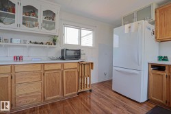 Kitchen featuring wood-finish flooring, white countertops, and both light wood base cabinetry and white upper cabinets - 