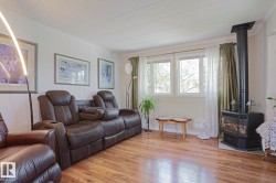 Living area featuring wood-finish flooring, white paneling, and a corner-set fireplace - 