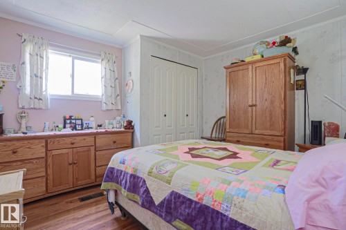 Bedroom featuring a double window, wood-finish flooring, a bi-fold closet door, and light-toned walls - 137 Lee Ridge Road Nw, Edmonton, AB - Indoor Photo Showing Bedroom