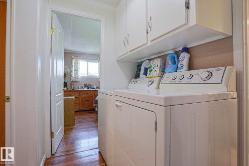 Dedicated laundry area featuring white upper cabinetry, a built-in shelf, and wood-finish flooring - 137 Lee Ridge Road Nw, Edmonton, AB - Indoor Photo Showing Laundry Room