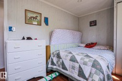 Bedroom featuring wood-finish flooring, light-toned wall paneling, and a recessed ceiling light - 