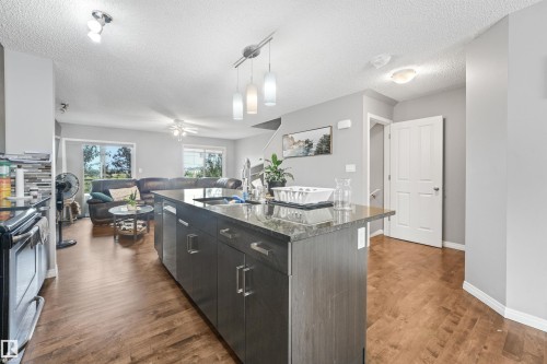Kitchen island featuring dark cabinetry, a countertop, and a double basin sink - #40 1030 Chappelle Bv Sw, Edmonton, AB - Indoor Photo Showing Kitchen