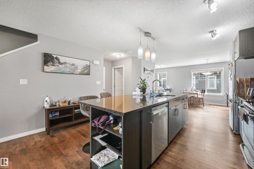 Spacious kitchen featuring a large central island with seating, stainless steel appliances, and pendant lighting - #40 1030 Chappelle Bv Sw, Edmonton, AB - Indoor Photo Showing Kitchen With Upgraded Kitchen