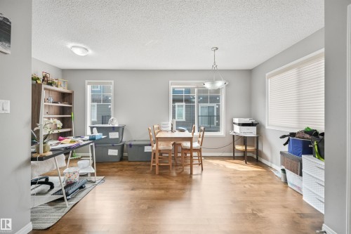 Expansive room featuring wood-finish flooring, light gray walls, and multiple windows with white blinds - #40 1030 Chappelle Bv Sw, Edmonton, AB - Indoor
