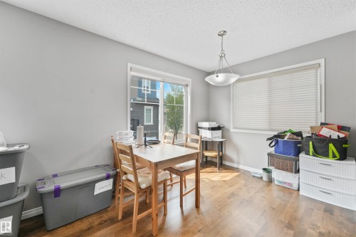 Spacious room featuring wood-finish flooring, two large windows, a ceiling-mounted light fixture, and light gray wall paint - #40 1030 Chappelle Bv Sw, Edmonton, AB - Indoor Photo Showing Dining Room