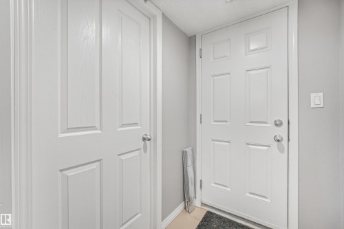 White paneled entryway door with satin nickel hardware and a light grey wall finish - #40 1030 Chappelle Bv Sw, Edmonton, AB - Indoor Photo Showing Other Room