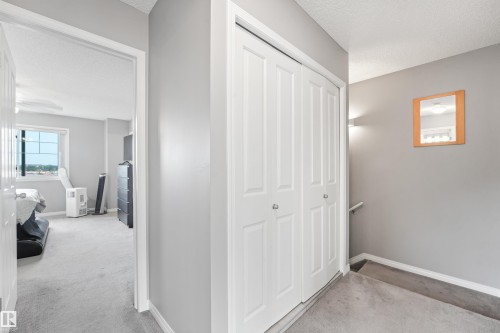 Hallway featuring bi-fold closet doors, light gray wall paint, and gray carpet flooring - #40 1030 Chappelle Bv Sw, Edmonton, AB - Indoor Photo Showing Other Room