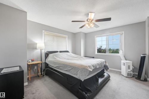 Carpeted room featuring light gray walls, a multi-pane window with white blinds, and a ceiling fan with integrated lighting - #40 1030 Chappelle Bv Sw, Edmonton, AB - Indoor Photo Showing Bedroom