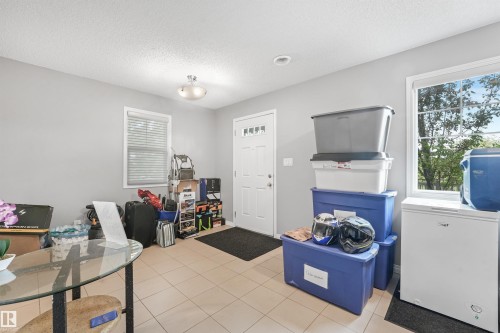 Utility space featuring light gray walls, tile flooring, a white paneled door, and two windows with white blinds - #40 1030 Chappelle Bv Sw, Edmonton, AB - Indoor