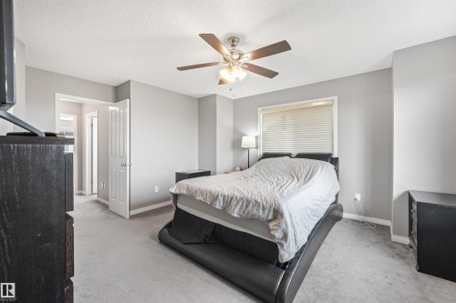 Spacious room featuring neutral gray walls, light gray carpeting, a ceiling fan with light fixture, and a window with horizontal blinds - #40 1030 Chappelle Bv Sw, Edmonton, AB - Indoor Photo Showing Bedroom