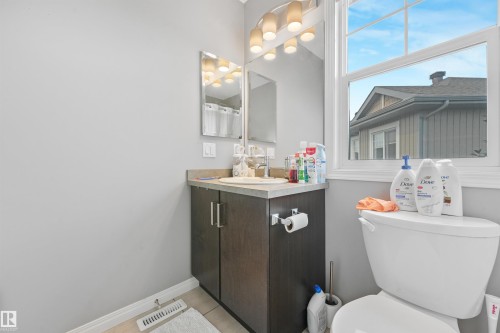 Bathroom vanity featuring a dark wood-finish cabinet with silver hardware, a countertop, an undermount sink with a chrome faucet, and an overhead vanity light fixture - #40 1030 Chappelle Bv Sw, Edmonton, AB - Indoor Photo Showing Bathroom