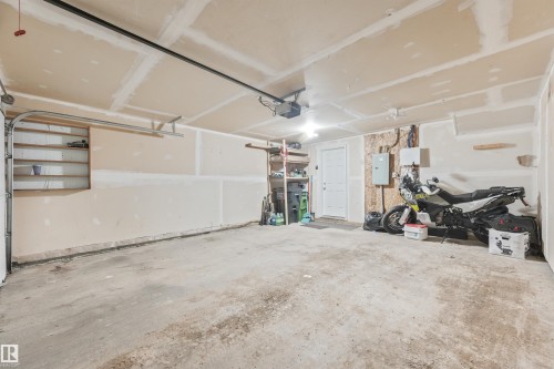 Spacious garage with concrete flooring, automatic garage door opener, and interior access door - #40 1030 Chappelle Bv Sw, Edmonton, AB - Indoor Photo Showing Garage