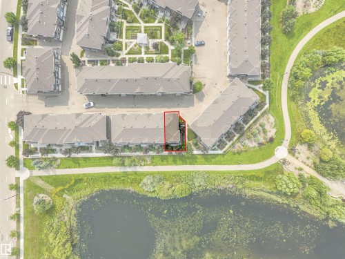 Aerial perspective of a multi-unit property with a dark-toned roof, bordering a paved pathway and a pond - #40 1030 Chappelle Bv Sw, Edmonton, AB -  With Body Of Water