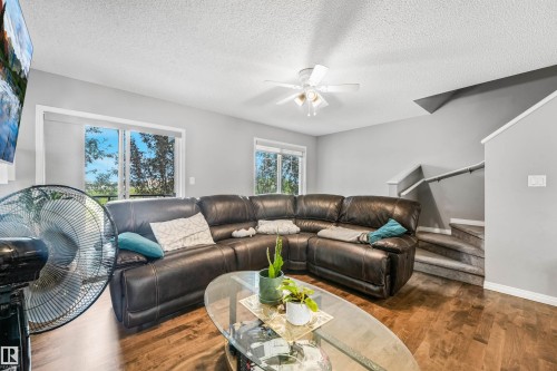Spacious living area featuring wood-finish flooring, light gray walls, and a ceiling fan - #40 1030 Chappelle Bv Sw, Edmonton, AB - Indoor Photo Showing Living Room