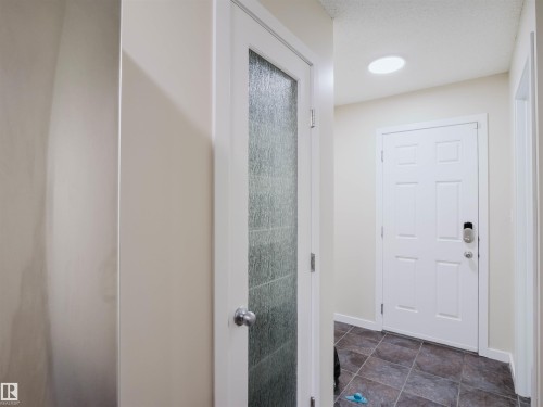 Entryway featuring a paneled door with smart lock hardware, recessed lighting, and large format tile flooring - 5407 14 Avenue Sw, Edmonton, AB - Indoor Photo Showing Other Room