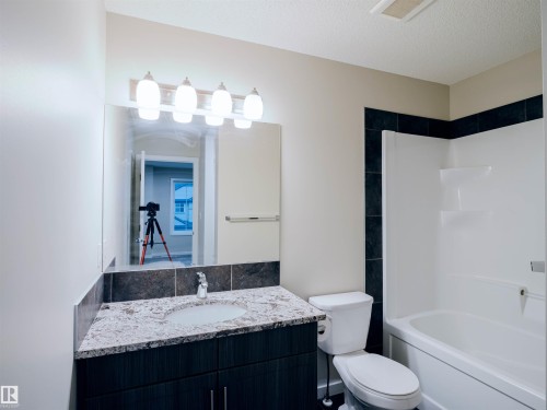 Bathroom featuring a vanity with a countertop, an undermount sink, and a two-door cabinet - 5407 14 Avenue Sw, Edmonton, AB - Indoor Photo Showing Bathroom