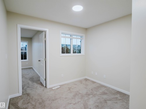 Neutral-toned carpeting paired with light wall finishes - 5407 14 Avenue Sw, Edmonton, AB - Indoor Photo Showing Other Room