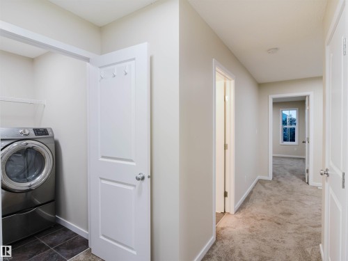 Dedicated laundry area featuring dark tile flooring and an integrated wire shelf - 5407 14 Avenue Sw, Edmonton, AB - Indoor Photo Showing Laundry Room