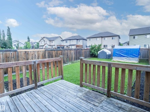 Outdoor wood deck with railing overlooking a fenced backyard featuring a manicured lawn and garden beds - 5407 14 Avenue Sw, Edmonton, AB - Outdoor With Deck Patio Veranda With Exterior