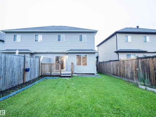 Expansive backyard featuring a green lawn, wood fencing, and a private wooden deck - 5407 14 Avenue Sw, Edmonton, AB - Outdoor With Exterior