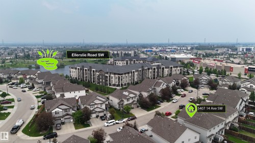 Aerial perspective showcasing a residential community with a large body of water, multi-story residential buildings, and commercial structures in the distance - 5407 14 Avenue Sw, Edmonton, AB - Outdoor With View