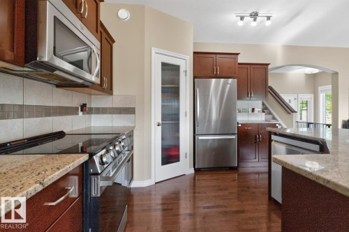 Kitchen featuring wood-finish flooring, stainless steel appliances, granite countertops, and a tile backsplash - 109 Selkirk Place, Leduc, AB - Indoor Photo Showing Kitchen With Upgraded Kitchen