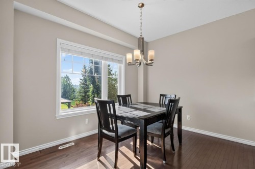 Dining area featuring wood-finish flooring, a contemporary chandelier, and a large window with white trim - 109 Selkirk Place, Leduc, AB - Indoor Photo Showing Dining Room