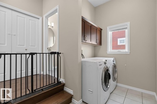 Dedicated laundry area featuring tile flooring, a window providing natural light, and upper cabinetry for storage - 109 Selkirk Place, Leduc, AB - Indoor Photo Showing Laundry Room