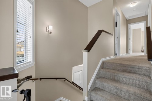 Carpeted staircase with dark wood-finish handrails and white newel posts - 109 Selkirk Place, Leduc, AB - Indoor Photo Showing Other Room