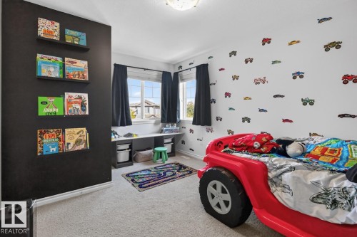 Carpeted room featuring a ceiling-mounted light fixture, multiple windows with dark drapes, and a built-in desk area - 109 Selkirk Place, Leduc, AB - Indoor Photo Showing Garage