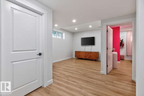 Spacious room featuring light wood-finish flooring, recessed lighting, and a window with security bars - 109 Selkirk Place, Leduc, AB - Indoor