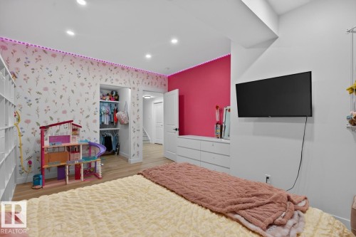 Recessed ceiling lighting, light wood-finish flooring, built-in shelving, a closet with a built-in hanging rod, and a wall-mounted television - 109 Selkirk Place, Leduc, AB - Indoor Photo Showing Other Room