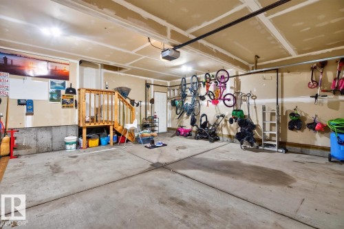 Spacious garage featuring concrete flooring, a wooden staircase, and built-in overhead lighting - 109 Selkirk Place, Leduc, AB - Indoor Photo Showing Garage