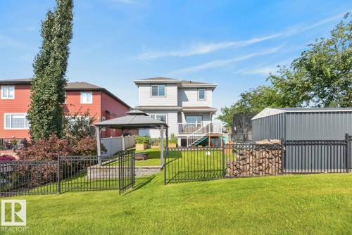 Expansive terraced backyard featuring a green lawn, black wrought iron fencing, a gazebo, and a metal storage shed - 109 Selkirk Place, Leduc, AB - Outdoor