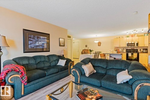 Open-concept living area with light-toned walls and wood-finish flooring - #203 17407 99 Av Nw, Edmonton, AB - Indoor Photo Showing Living Room