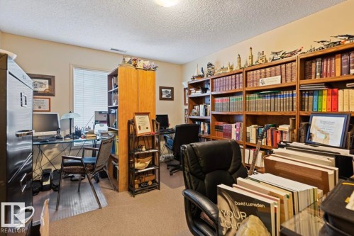 Versatile room featuring extensive built-in shelving, a dedicated desk area, light-colored walls, and neutral carpeting - #203 17407 99 Av Nw, Edmonton, AB - Indoor Photo Showing Office