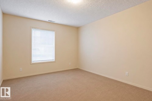 Room featuring neutral-toned walls, tan carpet, and a white window frame with horizontal blinds - #203 17407 99 Av Nw, Edmonton, AB - Indoor Photo Showing Other Room