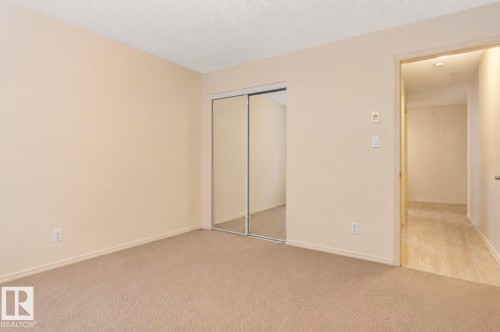 Neutral tone wall paint, textured ceiling, and plush carpeting - #203 17407 99 Av Nw, Edmonton, AB - Indoor Photo Showing Other Room
