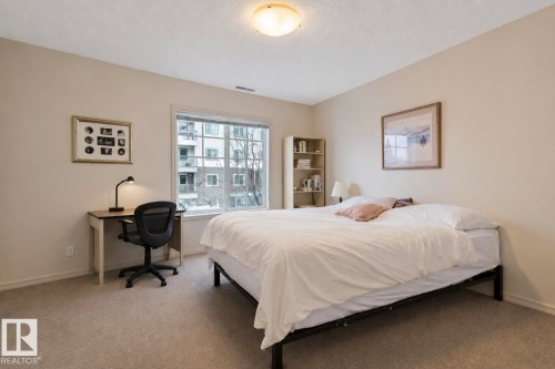 Bedroom featuring a large window, neutral wall paint, and textured carpeting - #203 17407 99 Av Nw, Edmonton, AB - Indoor Photo Showing Bedroom