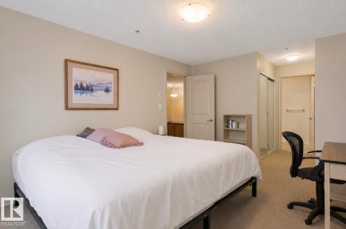 Carpeted bedroom featuring neutral wall tones and a ceiling-mounted light fixture - #203 17407 99 Av Nw, Edmonton, AB - Indoor Photo Showing Bedroom