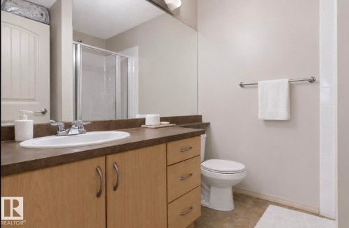 Bathroom featuring a single vanity with wood-finish cabinetry, a white oval undermount sink, and a dark countertop - #203 17407 99 Av Nw, Edmonton, AB - Indoor Photo Showing Bathroom
