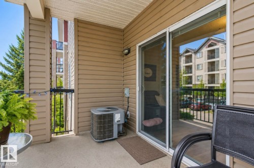 Outdoor balcony featuring concrete flooring, tan siding, and a black wrought iron railing - #203 17407 99 Av Nw, Edmonton, AB - Outdoor With Exterior