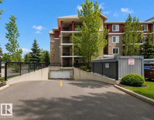 Multi-story residential building featuring balconies and a driveway leading to a subterranean parking garage - #203 17407 99 Av Nw, Edmonton, AB - Outdoor