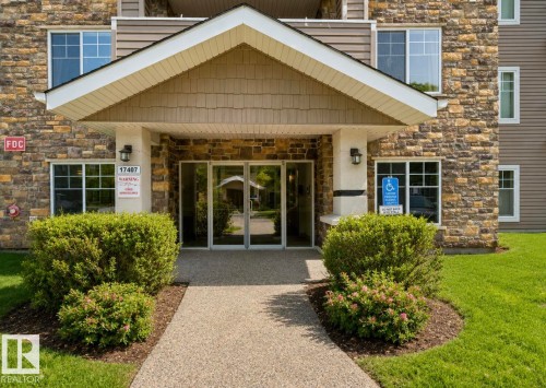Building entrance featuring stone veneer, siding, and a covered porch - #203 17407 99 Av Nw, Edmonton, AB - Outdoor