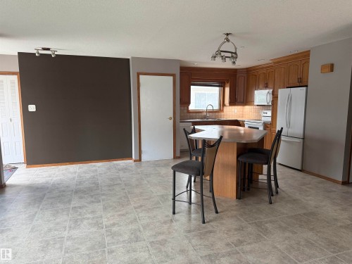 Kitchen featuring wood-finish cabinetry, a built-in microwave, and a double-door refrigerator - 1412 63 Street Nw, Edmonton, AB 