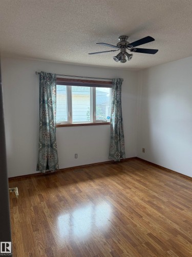 Wood-finish flooring throughout, ceiling fan with integrated lighting, and a large window providing natural illumination - 1412 63 Street Nw, Edmonton, AB 