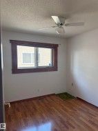 Wood-finish flooring, white walls, and a window with wood trim - 